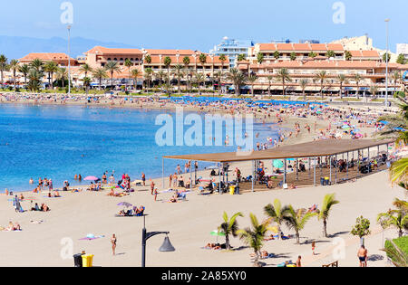 Tenerife, Spain - October 13, 2019: People sunbathing on sandy beach of Playa de los Cristianos, enjoy warm Atlantic Ocean waters, Tenerife, Spain Stock Photo