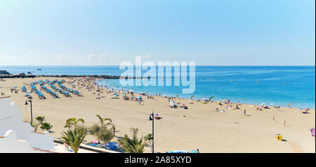 Tenerife, Spain - October 13, 2019: Panoramic view of crowd of people sunbathing on sandy beach of Playa de los Cristianos, enjoy warm weather, Spain Stock Photo