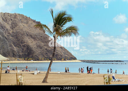 Tenerife, Spain - October 13, 2019: People sunbath on sandy picturesque cozy beach of Playa de Las Teresitas, Canary Islands, Spain Stock Photo