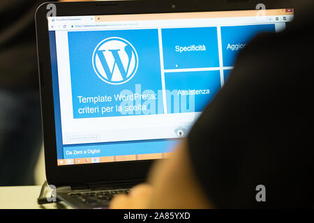 A laptop screen photographed with the Wordpress logo, partially visible from the operator's shoulders. Stock Photo