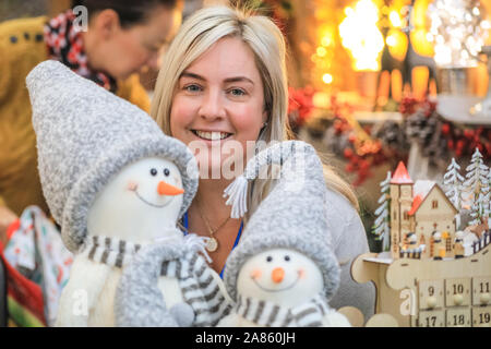 Olympia London, London, UK. 6th Nov, 2019. An assistant with decor company 'The 12 Days of Christmas' shows off their cute dcorative snowmen. This year's Spirit of Christmas Fair presents an unrivalled collection of 900 independent boutique retailers and designer-makers as well as over 100 artisan food producers at the majestic Olympia London exhibition halls. The fair is an exclusive Christmas shopping experience open to the public, and runs unitl Nov 10th this year. Credit: Imageplotter/Alamy Live News Stock Photo