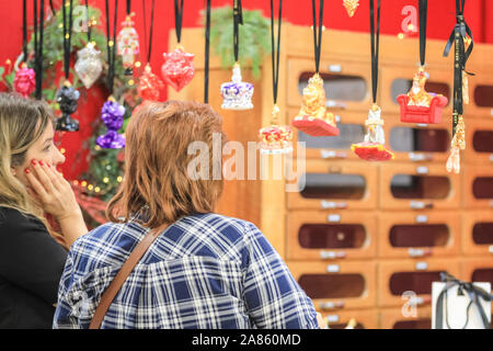 Olympia London, London, UK. 6th Nov, 2019. Keen shoppers select their decorations. The Aerloom London stall displays colourful, cheeky baubles and tree decor, including a Queen Elizabeth, Queen Victoria and British bulldog. This year's Spirit of Christmas Fair presents an unrivalled collection of 900 independent boutique retailers and designer-makers as well as over 100 artisan food producers at the majestic Olympia London exhibition halls. The fair is an exclusive Christmas shopping experience open to the public, and runs unitl Nov 10th this year. Credit: Imageplotter/Alamy Live News Stock Photo