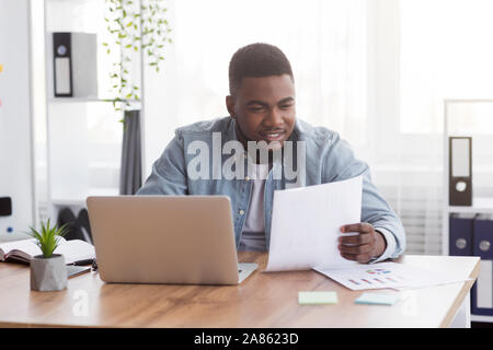 Black businessman working with documents in office, checking financial reports Stock Photo