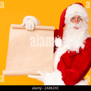 Santa holding big cardboard wish list with copy space for text Stock Photo