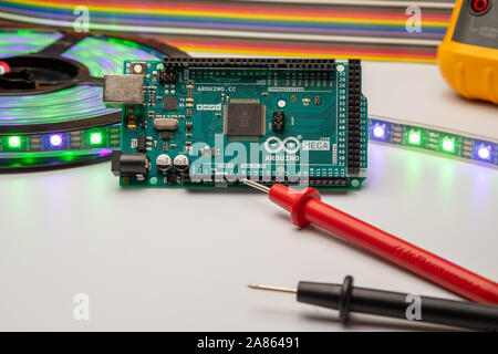 Arduino Mega2560 displayed with LED strip, multimeter, and jumper wire background. Stock Photo