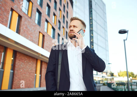 Businessman talking on the phone on the background of business building Stock Photo