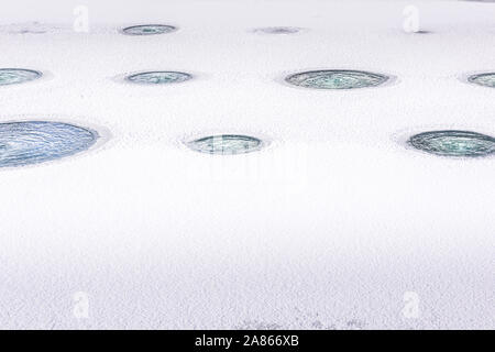 Horizontal lines of holes made in ice, that is covering aerated fish pond during winter season, aiming to protect fish population. Seasonal background Stock Photo