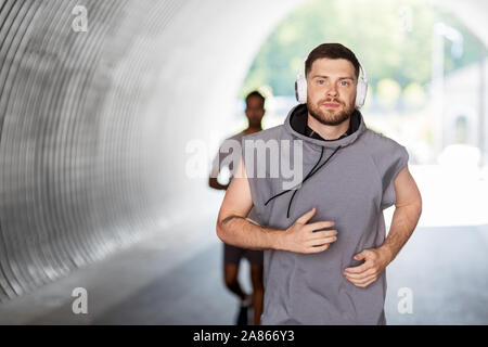 male friends with headphones running outdoors Stock Photo