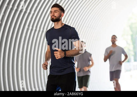 young men or male friends running outdoors Stock Photo