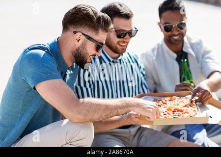 male friends eating pizza with beer on street Stock Photo