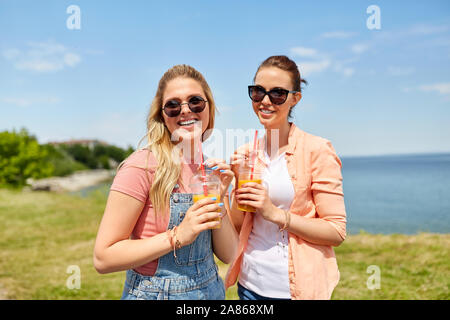 teenage girls or friends with drinks in summer Stock Photo