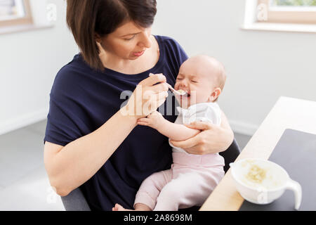 middle-aged mother feeding baby daughter at home Stock Photo