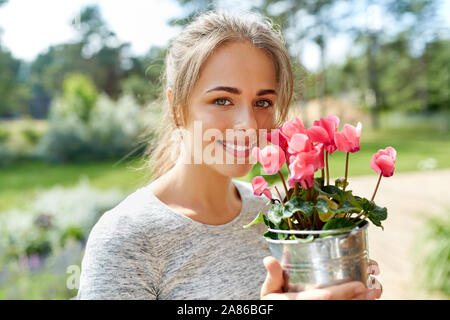 young woman with cyclamen flowers at summer garden Stock Photo