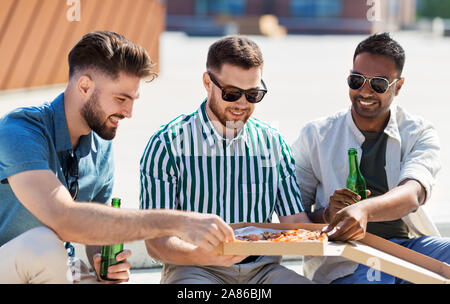 male friends eating pizza with beer on street Stock Photo