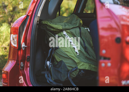 Close-up of green backpack and karemat in car back. Car packed for travel outdoors. Stock Photo