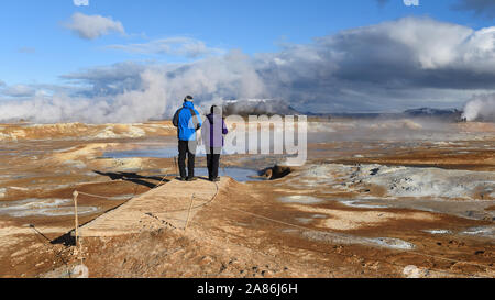 A couple of tourists watching The Namafjall Geothermal Area, located in Northeast Iceland, on the east side of Lake Myvatn. Stock Photo