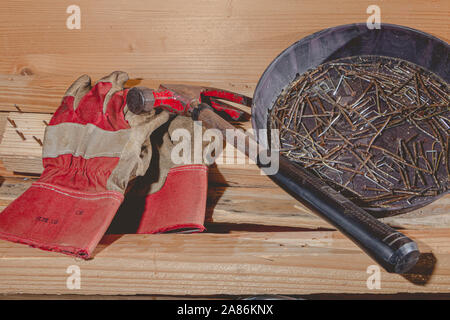 old rusty hammer and construction gloves laid on wooden board in studio Stock Photo