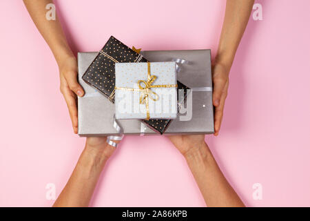 Hands give presents boxes over light pink background. Christmas, New Year, holidays concept Stock Photo
