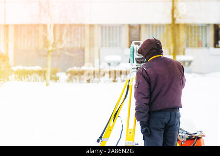 Surveyor engineer uses a total station at a construction site. Geodetic works. Building construction Stock Photo