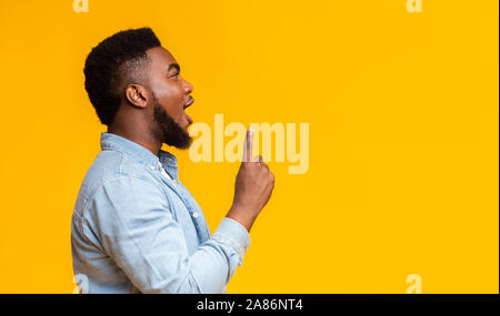 African guy looking and pointing upwards at copy space Stock Photo