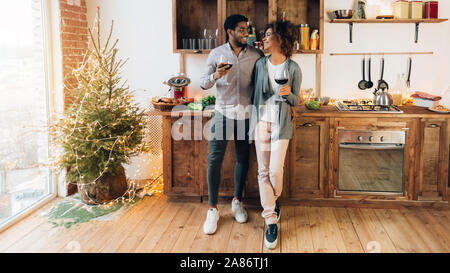 Young couple celebrating New Year drinking wine in kitchen