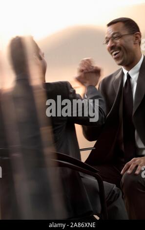 Black and Latino  businessmen give each other high five in meeting Stock Photo