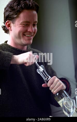 Man opening bottle of wine with corkscrew Stock Photo