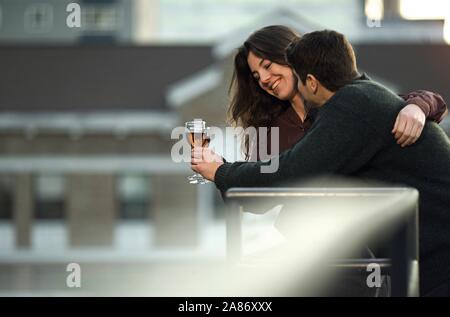 couple with drinks on an urban roof terrace Stock Photo