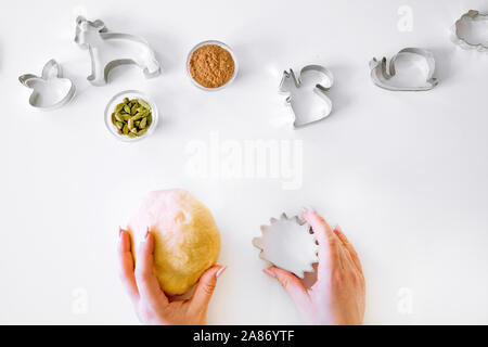 Female hand holding pastry and cookie cuttler, pastry preparation, top view. Cardamom and cinnamon spice on the backgrounds. Stock Photo