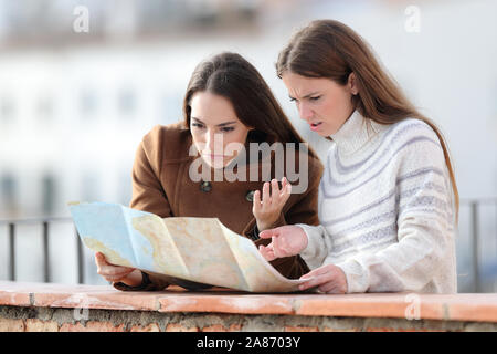 Lost tourists checking paper map in a balcony on winter holidays Stock Photo