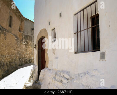 White stone house with a window behind bars on a narrow street Stock Photo