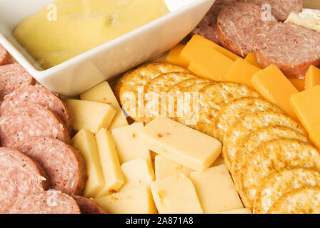 meat and cheese delicatessen tray including stone wheat crackers, wheat crackers, summer sausage, cheddar cheese, pepper jack cheese and a sauce. Stock Photo