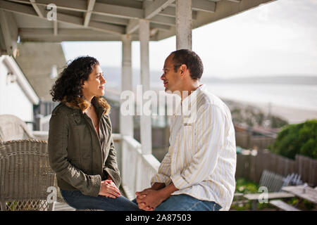 Happy young couple talking on a verandah. Stock Photo