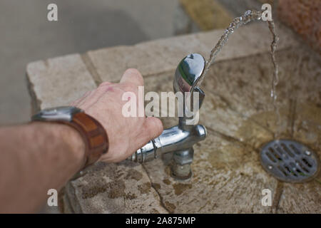 Man turning on drinking fountain Stock Photo