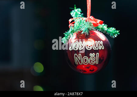 Merry Christmas written in french on a red Christmas ball on a black background Stock Photo