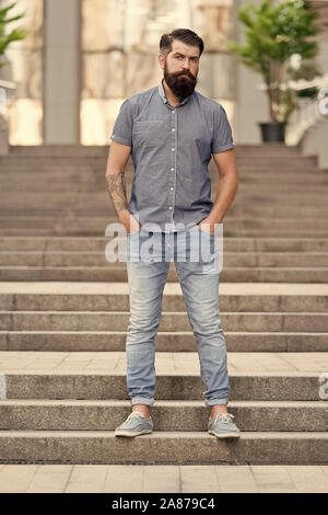 In love with denim. Man bearded hipster fashion model wear denim clothes  urban background stairs. Regular walk in city center. Confident guy wear  jeans denim trousers and shirt. Comfortable outfit Stock Photo 