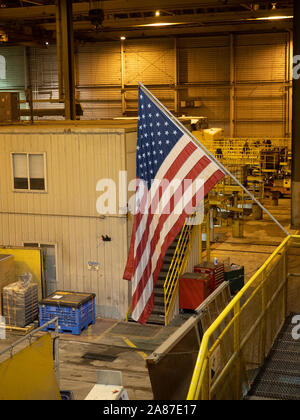 American flag hanging indoors in a factory with tools and storage crates on the platform. Stock Photo