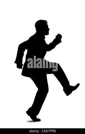 Silhouette of a backlit model posing as a businessman on a white background.  He is jumping up or leaping forward. Stock Photo