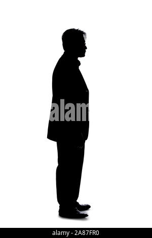 Silhouette of a backlit model posing as a businessman on a white background.  He is standing and waiting patiently Stock Photo