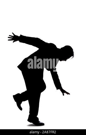 Silhouette of a backlit model posing as a businessman on a white background.  He is balancing or slipping and falling due to an accident Stock Photo