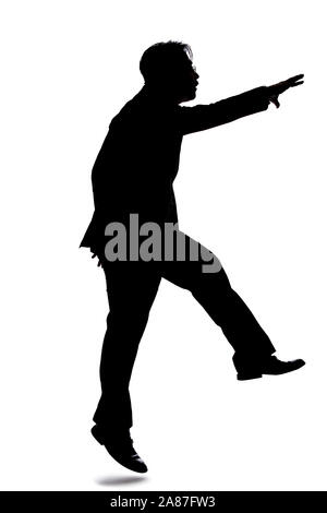 Silhouette of a backlit model posing as a businessman on a white background.  He is jumping up or leaping forward. Stock Photo