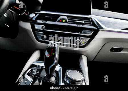 Automatic gear stick of a modern car. Modern car interior details. Close up view. Car detailing. Automatic transmission lever shift. White leather int Stock Photo