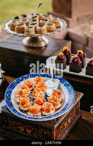 Pastry bar assorted  pastries, smoked salmon with cream cheese and dessert chocolate cake in beautiful ceramic plate and tray Stock Photo