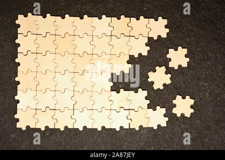 Half ordered puzzle with white jigsaw pieces. One side of the image shows part of the completed puzzle, other side shows the work in progress on a tex Stock Photo