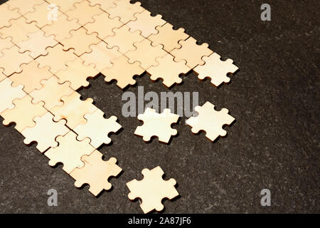 Half ordered puzzle with white jigsaw pieces. One side of the image shows part of the completed puzzle, other side shows the work in progress on a tex Stock Photo