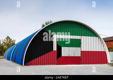 Close-up of the national flag of Kuwait  painted on the metal wall of a large warehouse the closed territory against blue sky. The concept of storage Stock Photo