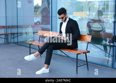 Man in suit arabic puts on sunglasses with tablet near business center Stock Photo
