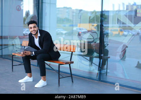 Man in suit arabic puts on sunglasses with tablet near business center Stock Photo