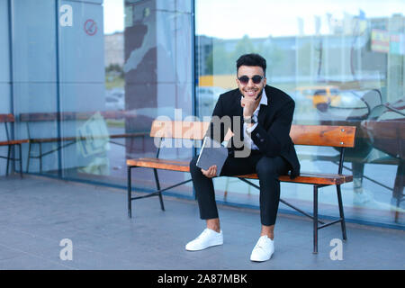 Man in suit arabic puts on sunglasses with tablet near business center Stock Photo
