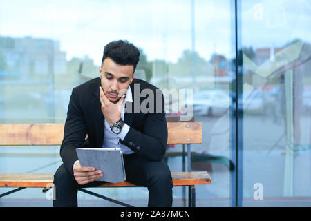 Man in suit arabic puts on sunglasses with tablet near business center Stock Photo